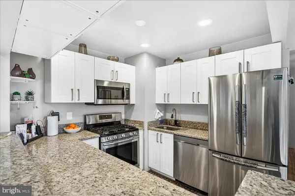 a kitchen with granite countertop white cabinets and stainless steel appliances