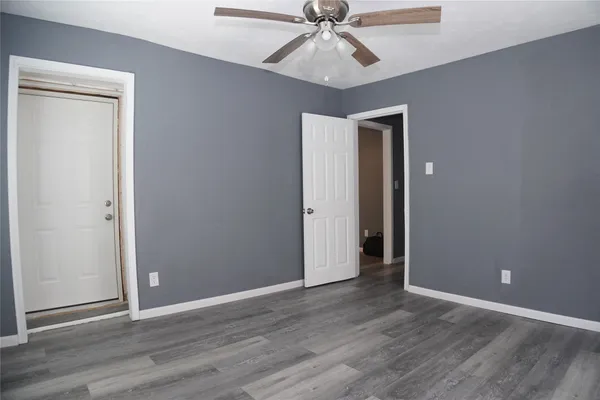 an empty room with wooden floor closet and fan