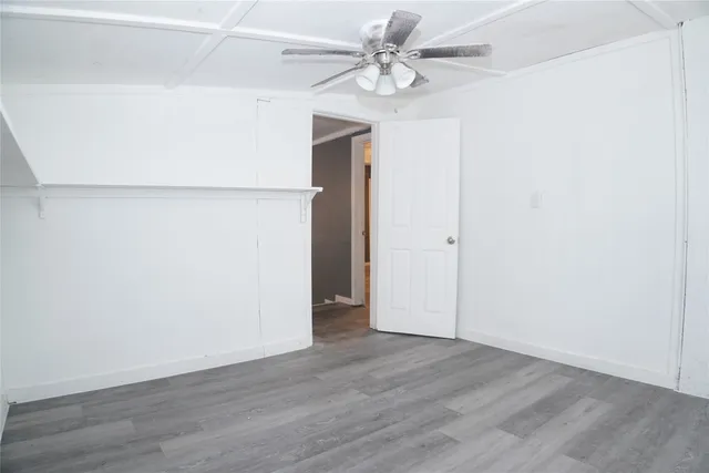 an empty room with wooden floor and ceiling fan