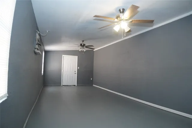 an empty room with a chandelier fan and windows