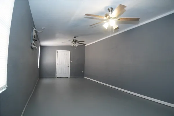 an empty room with a chandelier fan and windows