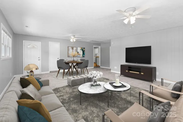 a living room with furniture a flat screen tv and kitchen view