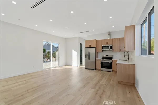 a large kitchen with stainless steel appliances a refrigerator and a stove top oven