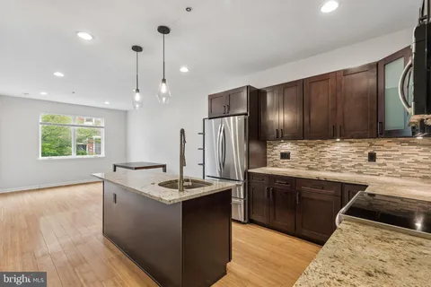 a kitchen with kitchen island granite countertop a sink stainless steel appliances and cabinets