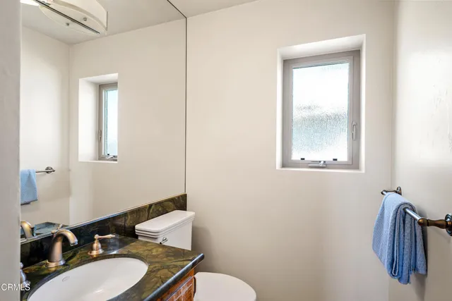 a bathroom with a granite countertop sink vanity mirror and toilet