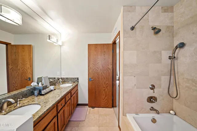 a bathroom with a tub sink double vanity and shower
