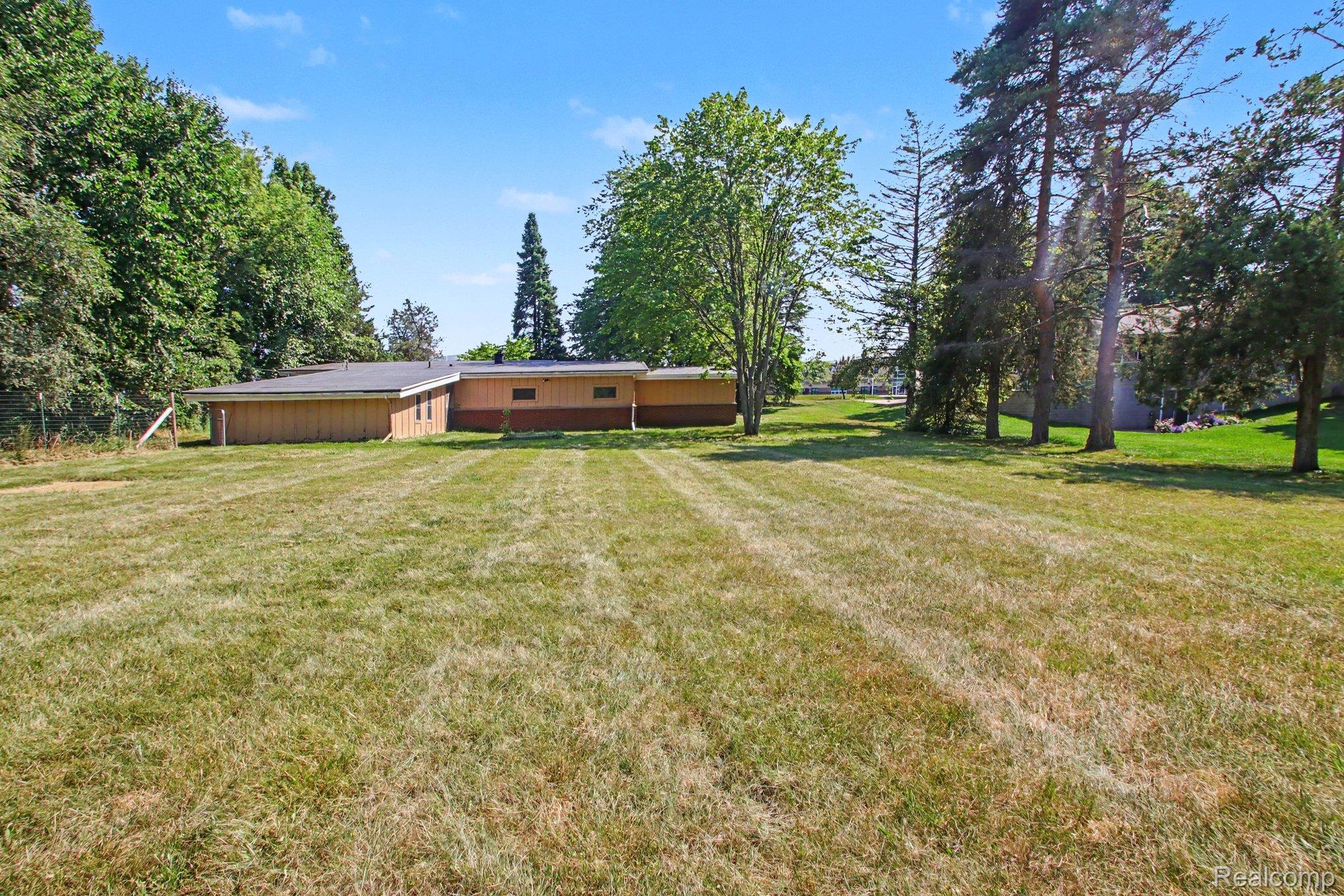 7800 Sharpe Road Fowlerville, MI 48836 - Photo 22 of 22 Expansive level grounds featuring mature landscaping and established trees, offering substantial outdoor space with open lawn areas ideal for recreation and future development potential