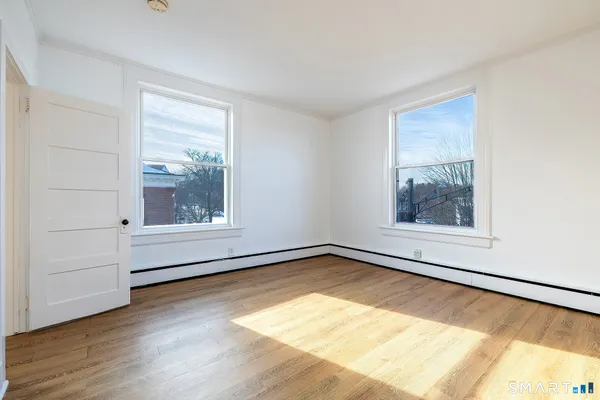 a view of an empty room with a window and wooden floor