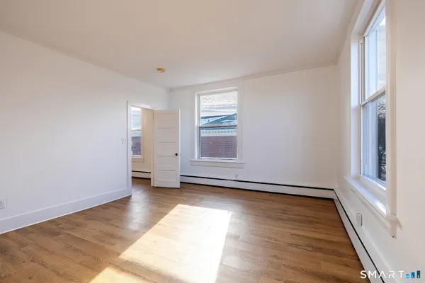 a view of an empty room with wooden floor and a window
