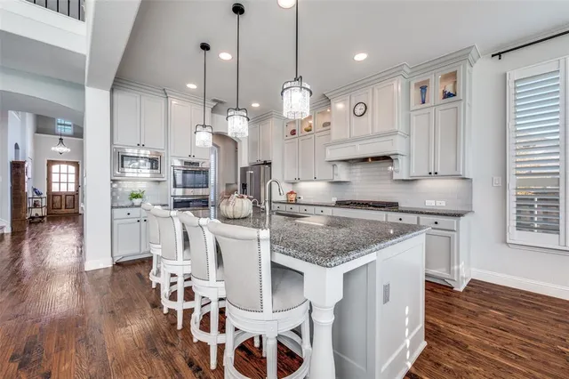 a kitchen with stainless steel appliances granite countertop a stove refrigerator and a dining table with wooden floor