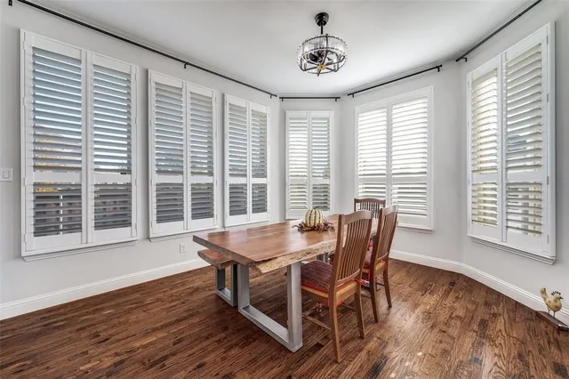 a dining room with wooden floor a chandelier a wooden table and chairs