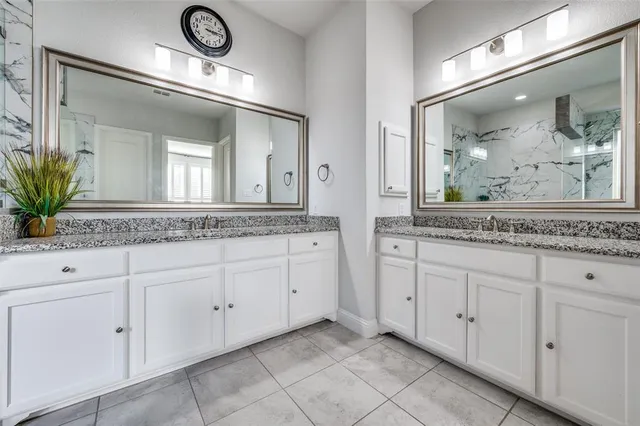 a bathroom with white cabinets and a mirror