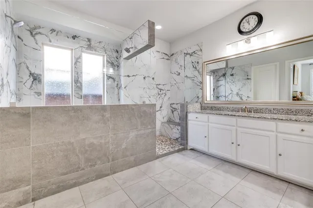 a spacious bathroom with a granite countertop sink a mirror and shower