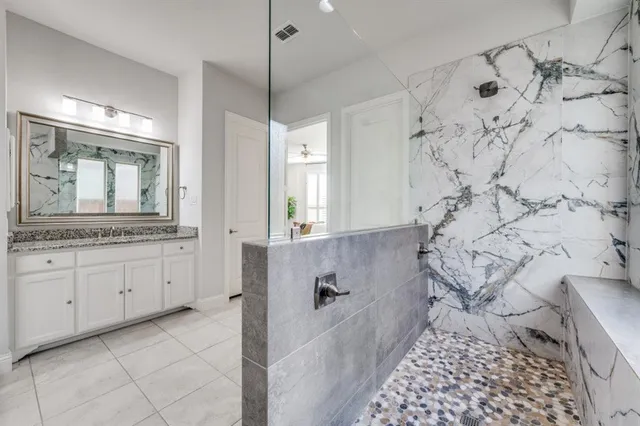 a spacious bathroom with a granite countertop sink a mirror a vanity and a bathtub