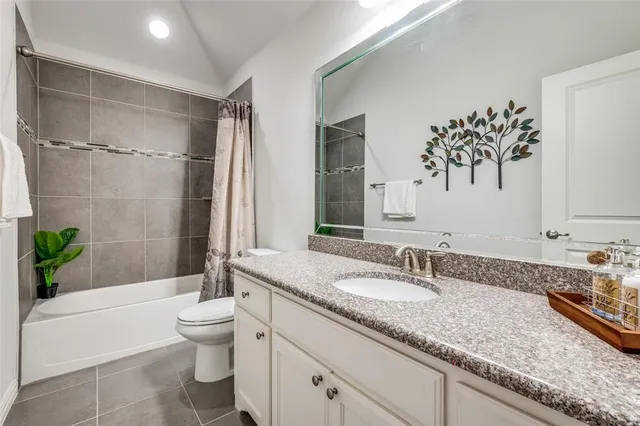 a bathroom with a granite countertop sink a toilet a mirror a bathtub and shower