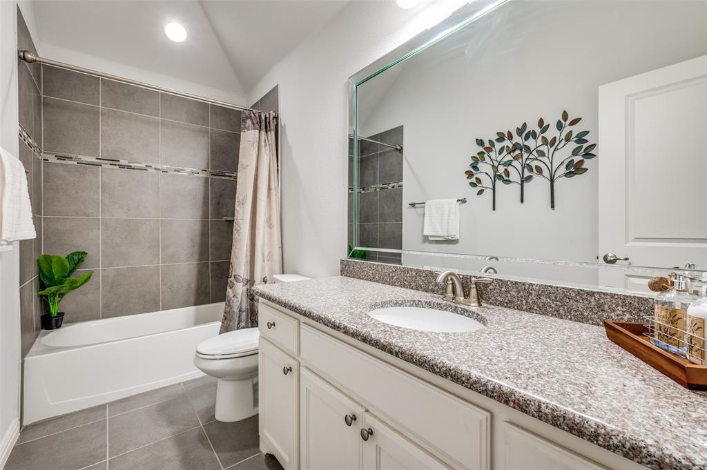 2631 Seabiscuit Road Celina, TX 75009 - Photo 28 of 40 a bathroom with a granite countertop sink a toilet a mirror a bathtub and shower