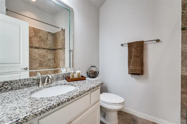 a bathroom with a granite countertop sink toilet and mirror