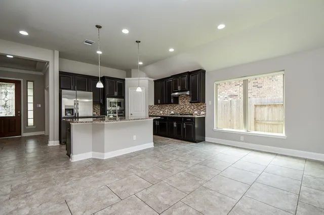 a large white kitchen with a large window and stainless steel appliances
