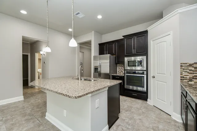 a kitchen with stainless steel appliances granite countertop a sink refrigerator and cabinets