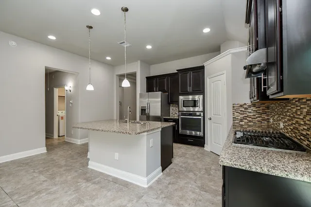 a kitchen with stainless steel appliances kitchen island granite countertop a refrigerator and a stove