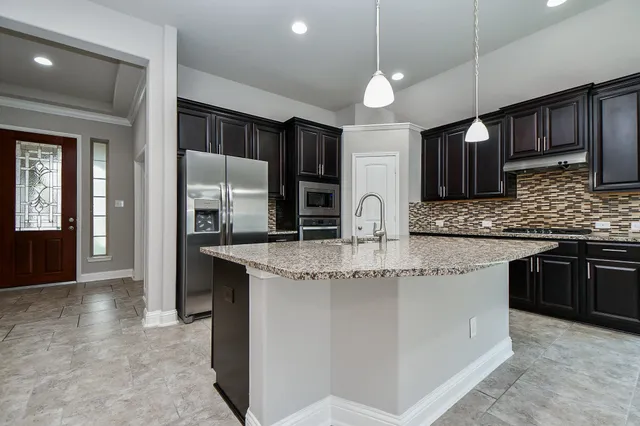 a kitchen with stainless steel appliances granite countertop a sink and a refrigerator