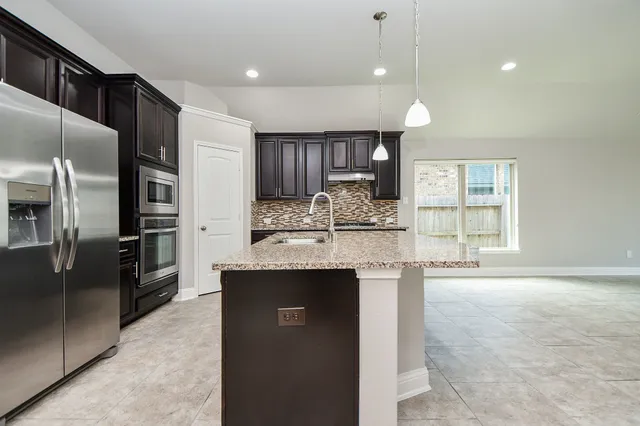 a kitchen with kitchen island a counter top space stainless steel appliances and a window