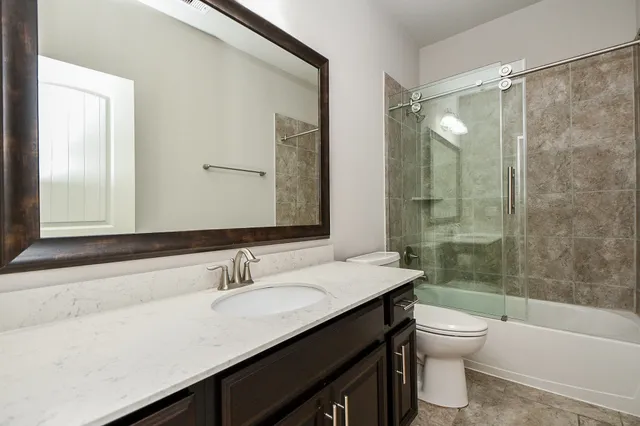 a bathroom with a shower sink vanity mirror and toilet