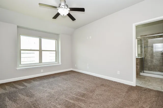 an empty room with chandelier fan and windows