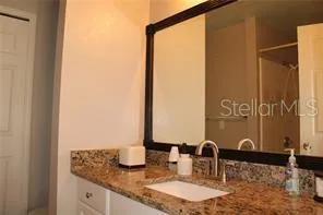a bathroom with a granite countertop sink and a mirror