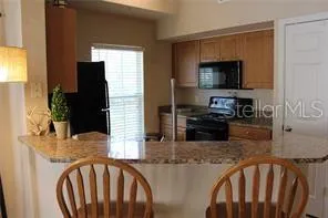 a kitchen with stainless steel appliances kitchen island granite countertop a refrigerator a stove top oven a sink and dishwasher