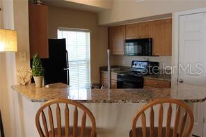 5681 Bidwell Parkway, Unit 204 Sarasota, FL 34233 - Photo 2 of 41 a kitchen with stainless steel appliances kitchen island granite countertop a refrigerator a stove top oven a sink and dishwasher