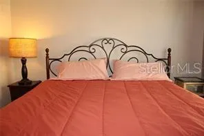 a bedroom with a bed and a lamp on dresser