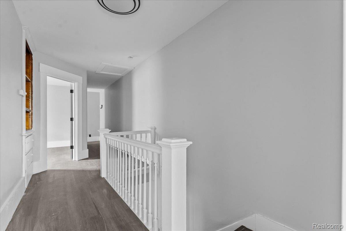 58 East Philadelphia Street Detroit, MI 48202 - Photo 13 of 24 Hallway with wood-finish flooring, white spindle railing, light gray walls, white trim, and a built-in shelving unit with drawers