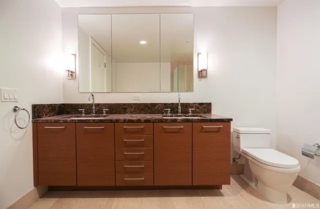 a bathroom with a granite countertop toilet sink and mirror