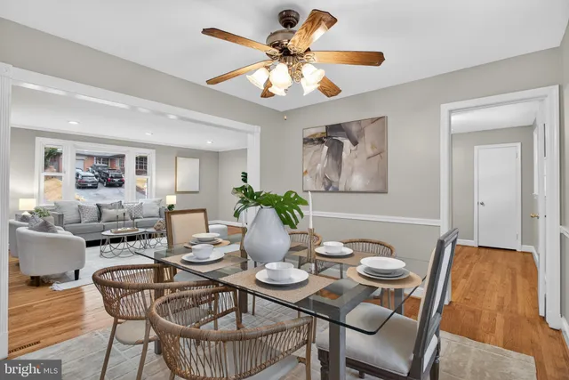a dining room with furniture and a chandelier fan