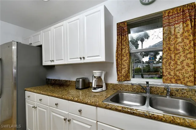 a kitchen with granite countertop a sink a stove and cabinets