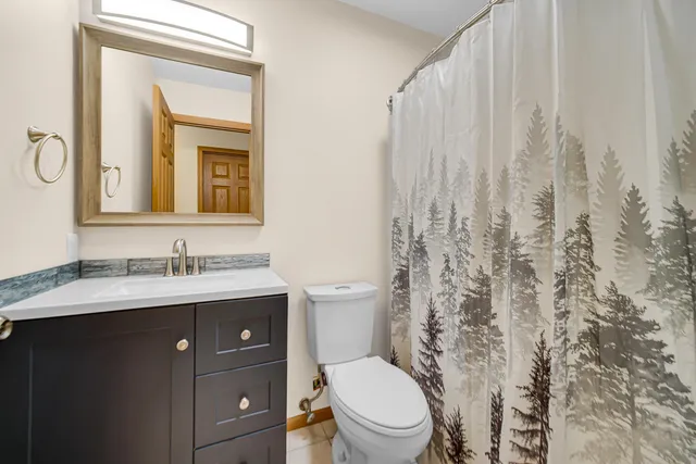 a bathroom with a granite countertop toilet a sink a mirror and a shower