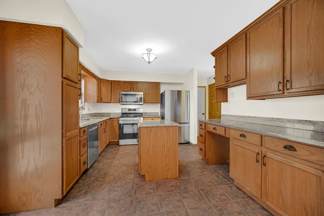 a kitchen with stainless steel appliances granite countertop a stove top oven a sink a refrigerator and cabinets