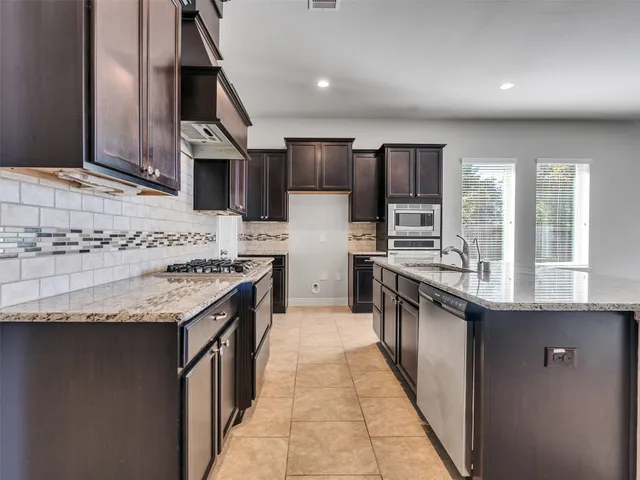 a kitchen with stainless steel appliances granite countertop a sink and a stove