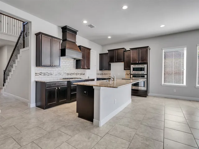a kitchen with kitchen island granite countertop a stove sink and cabinets