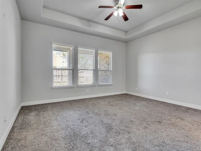 an empty room with chandelier fan and windows