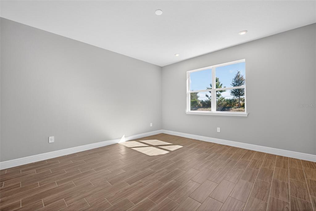 12349 49th Street East Parrish, FL 34219 - Photo 13 of 38 a view of an empty room with wooden floor and a window
