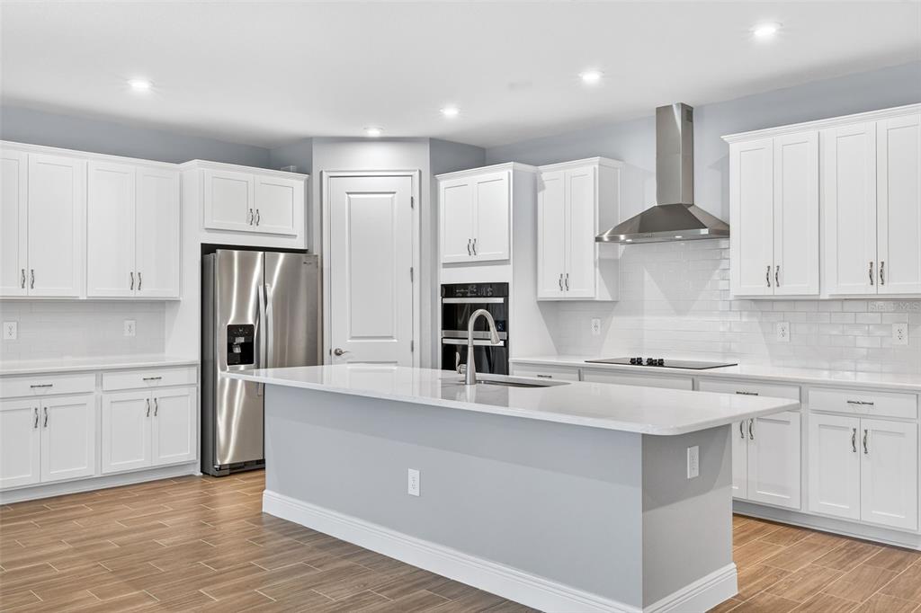 12349 49th Street East Parrish, FL 34219 - Photo 5 of 38 a kitchen with stainless steel appliances granite countertop a refrigerator sink and white cabinets