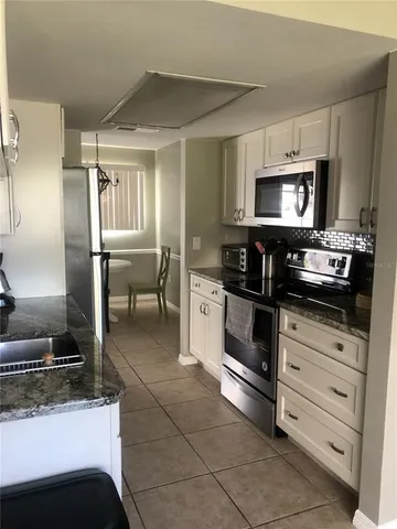 a kitchen with granite countertop a stove a microwave and a refrigerator