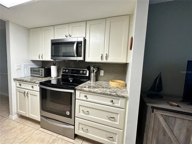 a kitchen with stainless steel appliances granite countertop a stove microwave and refrigerator