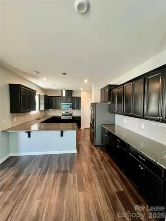a large white kitchen with stainless steel appliances kitchen island granite countertop a stove and a sink