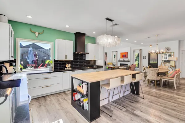 a kitchen with stainless steel appliances kitchen island granite countertop a table chairs and a refrigerator
