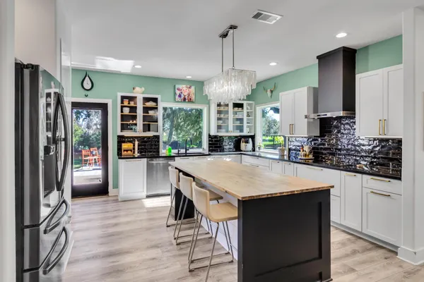 a large kitchen with stainless steel appliances kitchen island granite countertop a refrigerator oven a sink dishwasher and a fireplace with wooden floor