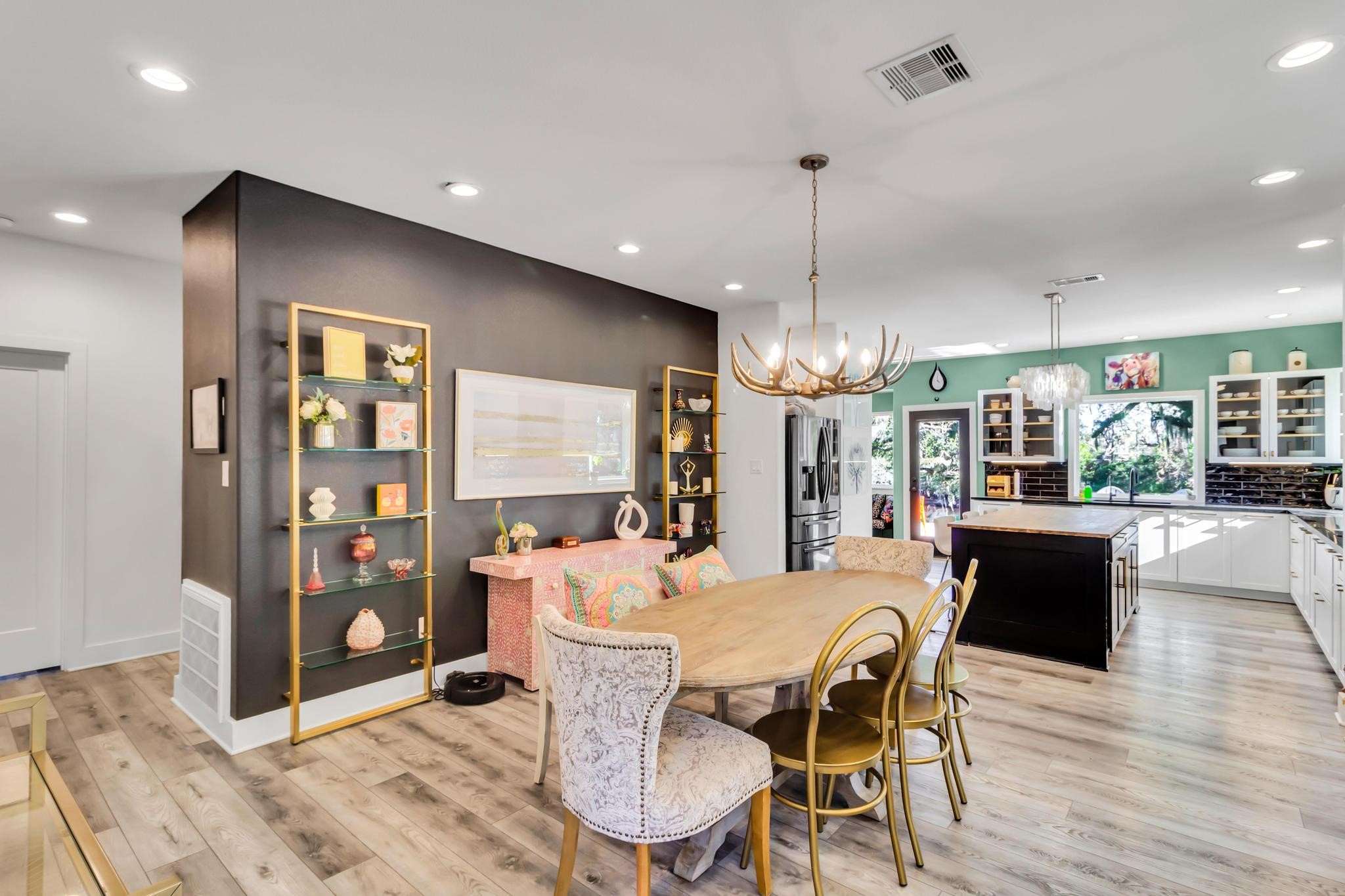 295 County Road 687 Angleton, TX 77515 - Photo 24 of 38 This home features a modern, open-concept kitchen and dining area with elegant lighting and stylish decor. The glass shelves and a dark accent wall add sophistication, while natural light floods the space through large windows, creating a bright and inviting atmosphere.