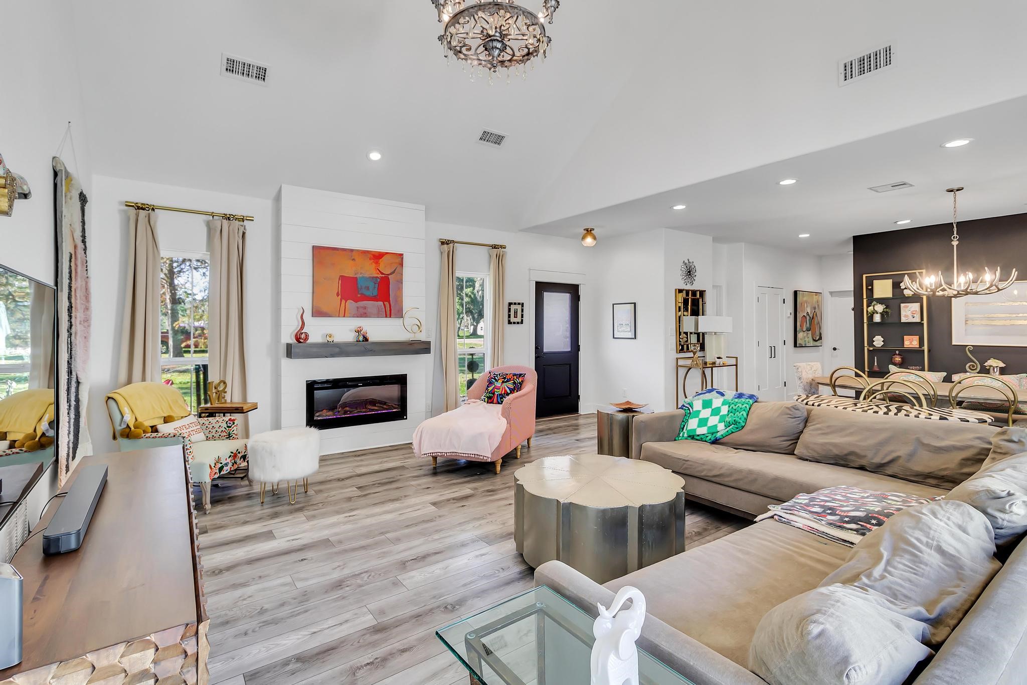 295 County Road 687 Angleton, TX 77515 - Photo 38 of 38 This spacious living area features modern decor with a cozy electric fireplace, elegant light fixtures, and large windows for natural light. The open floor plan seamlessly connects to a stylish dining area, offering a welcoming and functional space ideal for entertaining.
